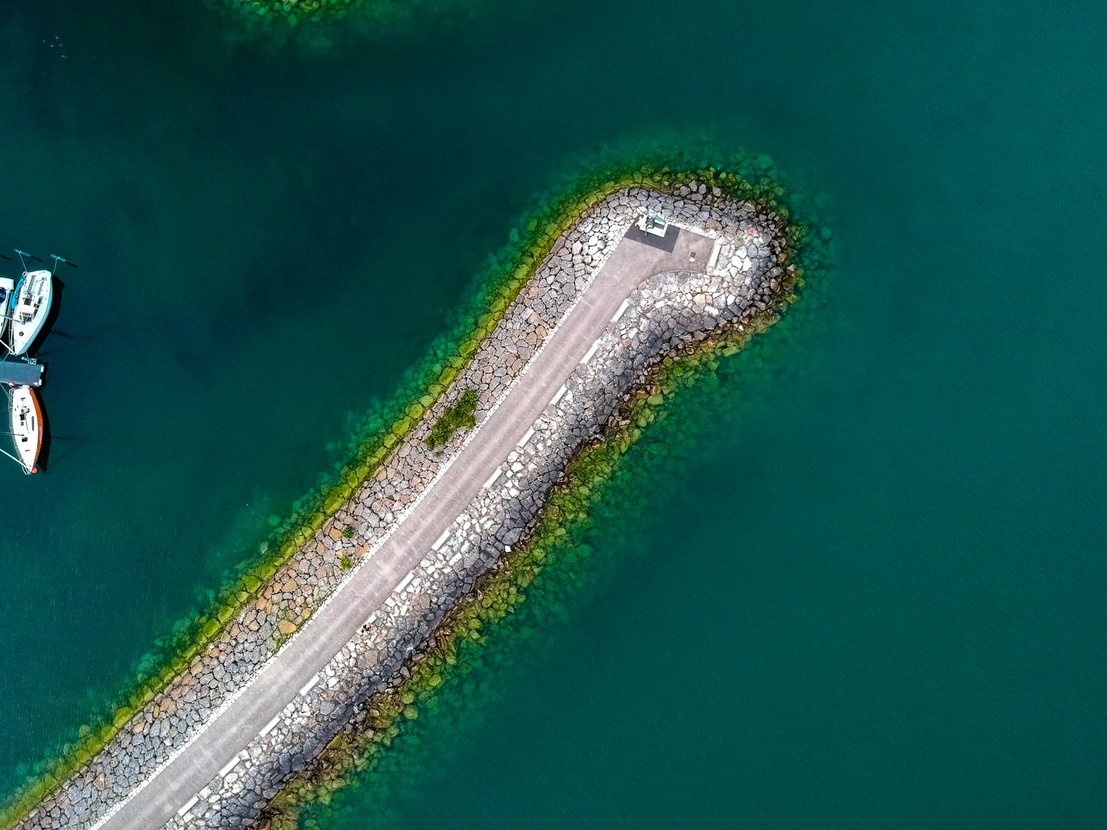 birds eye view of concrete road surrounded by body of water